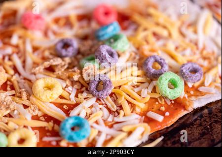 Pizza von einem Kind mit Müsli, Käse und Sauce. Stockfoto