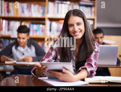 Ich werde lernen. Porträt einer attraktiven Studentin, die ihr digitales Tablet während des Unterrichts benutzt. Stockfoto