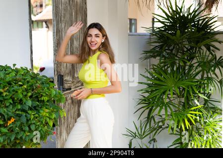 Willkommen. Porträt einer fröhlichen Frau, die in der Tür einer modernen Villa steht, Besucher und Gast, die das Haus verlassen, glücklich Stockfoto