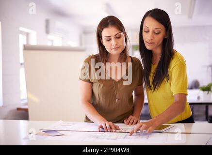 Was halten Sie davon, diesen Eingang zu verschieben... zwei Designerinnen, die die Details eines Bauplans diskutieren. Stockfoto