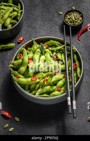 Edamamabohnensalat in Hülsen mit Chili-Pfeffer auf schwarzem Hintergrund Stockfoto