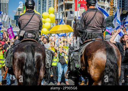 Tel Aviv, Israel. 09. März 2023. Demonstranten sehen sich während einer Demonstration aufgebauten Polizeibeamten gegenüber. Zehntausende Demonstranten marschierten in Tel Aviv und blockierten den Tel Aviv Ayalon Highway, um den Verkehr zu wichtigen Industrie- und Hightech-Gebieten im ganzen Land zu stoppen, als Protest gegen den Justizreformplan der Regierung. Die Straßen wurden am Donnerstagmorgen im ganzen Land blockiert, als die Demonstranten einen "Tag des Widerstands" gegen die Pläne der Regierung zur Generalüberholung der Justiz einleiteten. (Foto: Eyal Warshavsky/SOPA Images/Sipa USA) Guthaben: SIPA USA/Alamy Live News Stockfoto