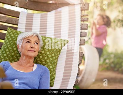 Gartenbesprechung. Eine Seniorin, die nachdenklich aussah, während sie sich im Hof entspannte. Stockfoto