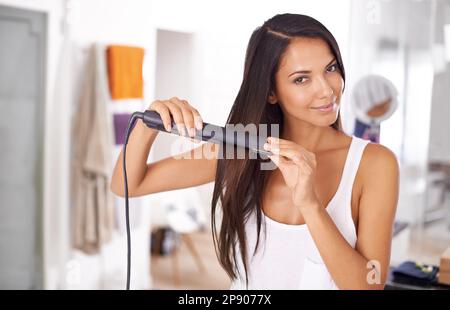 Mein Haar so zu stylen, wie ich es mag. Porträt einer schönen jungen Frau, die ihr Haar glättet. Stockfoto