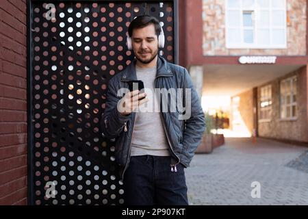 Erfolgreicher europäischer Freiberufler, der im Freien Podcast mit Kopfhörern hört Stockfoto