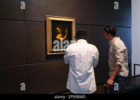 Leute, die Leonardo da Vincis Gemälde Johannes der Täufer genießen. Im Kunstmuseum des französischen Louvre in Abu Dhabi, Vereinigte Arabische Emirate. Stockfoto