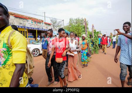 Die Menschen parieren mit maskierten Figuren durch die Straßen von Dedougou während des Festima Festivals, Dedougou, Burkina Faso Stockfoto