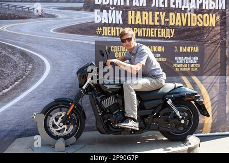 St. Petersburg, Russland-circa August 2018: Ein Mann mit Brille wird auf einem Harley-Davidson-Motorrad fotografiert. Motorrad-Tombola bei den Harley Days fes Stockfoto