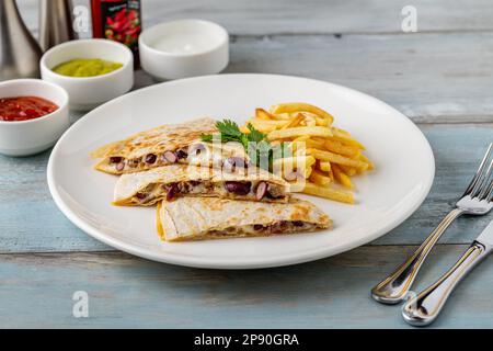Mexikanische Quesadilla mit Sauce und pommes frites auf einem weißen Porzellanteller Stockfoto