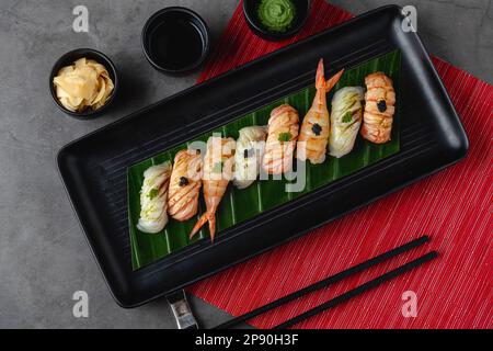 Sushi-Set mit verschiedenen Produkten auf einem schwarzen Steinteller Stockfoto