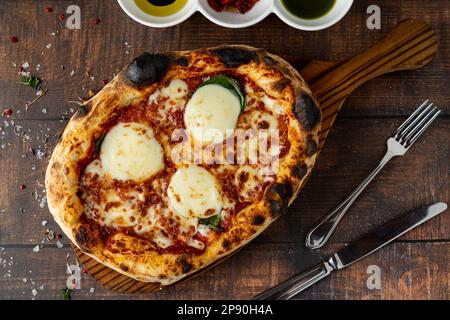 Italienische Pizza mit vier Käsesorten und viel Mozzarella auf einem Schneidebrett Stockfoto
