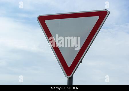 Straßenschild am Himmel. Weißes Dreieck mit rotem Rand. Signal, Platz machen. Sommertag. Stockfoto