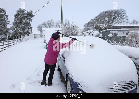 Teesdale, County Durham, Großbritannien. 10. März 2023 Wetter in Großbritannien. Nach heftigem Schneefall beginnt eine Frau in Teesdale, County Durham, Schnee von ihrem Auto zu entfernen. Derzeit gibt es eine gelbe Wetterwarnung, aber es wird erwartet, dass sich die Bedingungen im Laufe des Tages verbessern. Kredit: David Forster/Alamy Live News Stockfoto