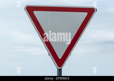 Straßenschild am Himmel. Weißes Dreieck mit rotem Rand. Signal, Platz machen. Sommertag. Stockfoto