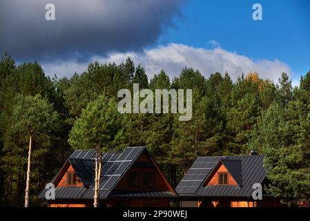 Photovoltaikanlage auf den Dächern von Holzhäusern im Wald Stockfoto