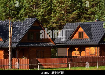 Photovoltaikanlage auf den Dächern von Holzhäusern im Wald Stockfoto