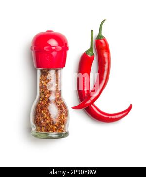 Trockene Chili-Pfefferflocken. Zerkleinerte rote Paprika in der Mühle und frische rote Paprika, isoliert auf weißem Hintergrund. Stockfoto