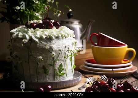 Wunderschöner Kekskuchen mit süßer Kirsche dekoriert mit natürlichen Blumen Stockfoto