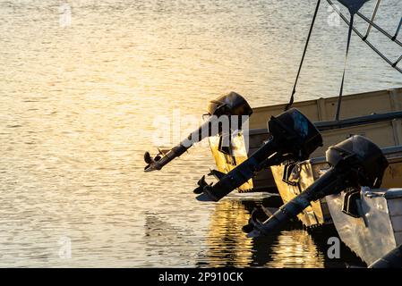 Eine Reihe von drei Außenbordmotorbooten in einer Reihe, die in ruhigem Wasser in der späten Nachmittagssonne in New South Wales, Australien, geparkt sind Stockfoto