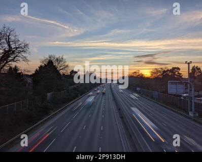 Ein Blick auf den Verkehr, der auf der Autobahn M3 zwischen den Abzweigungen 3 und 4 in Surrey in der Abenddämmerung fließt Stockfoto