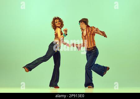 Brandtanz. Emotionaler Mann und Frau in Retro-Kleidung, tanzen Disco, tanzen auf grünem Hintergrund. Das Konzept der Modetrends 70s, 1980er Stockfoto