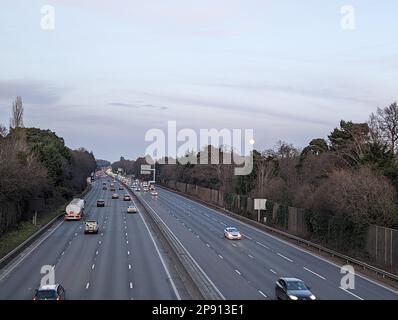 Ein Blick auf den Verkehr, der auf der Autobahn M3 zwischen den Abzweigungen 3 und 4 in Surrey in der Abenddämmerung fließt Stockfoto