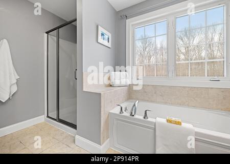 Ein sauberes Bad mit Dusche, Badewanne und großem Fenster Stockfoto