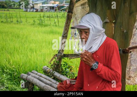 Ein Landwirt macht eine Pause unter einem provisorischen Haus auf einem kleinen Ackerland in Teresa. Die Landwirte auf den Philippinen stehen vor einer Vielzahl sozialer Probleme. Eines der schwerwiegendsten sozialen Probleme ist die Landlosigkeit, die durch die unzureichende Unterstützung der Regierung noch verschärft wird. Viele philippinische Bauern sind gezwungen, als Pächter oder Teilhaber zu arbeiten, wobei sie wenig Sicherheit und Kontrolle über ihr eigenes Land haben. Darüber hinaus leiden die Landwirte unter den drohenden Düngemittelpreisen, die über 2000 Pesos (40 USD) pro Sack liegen, was zu einem niedrigen Einkommen führt und sich negativ auf ihren Lebensunterhalt auswirkt. Stockfoto