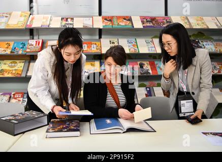 Bologna, Italien. 7. März 2023. Chen Lu (R), Copyright-Manager der China Science and Technology Press, spricht mit einem Besucher auf der Bologna Children's Book Fair in Bologna, Italien, am 7. März 2023. ZUM MOTTO „Feature: Chinesische Geschichten gewinnen die Herzen der Verleger auf der Kindermesse in Italien“: Jin Mamengni/Xinhua/Alamy Live News Stockfoto