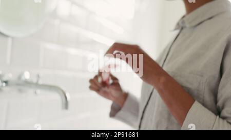 Hautpflege, Gesichtswalze und schwarze Frau, die während ihrer Schönheitsroutine im Gesicht Öl verwendet, für glatte, weiche und klare Haut im Badezimmer zu Hause. Eine Frau Stockfoto