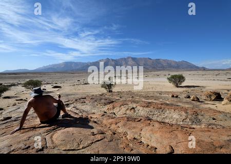 Ein Mann mit Bier schaut auf den Brandberg, Namibia Stockfoto