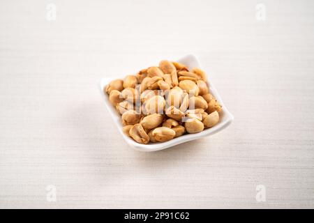 Würziger Erdnusskern in einer Schüssel auf weißem Tischhintergrund. Stockfoto