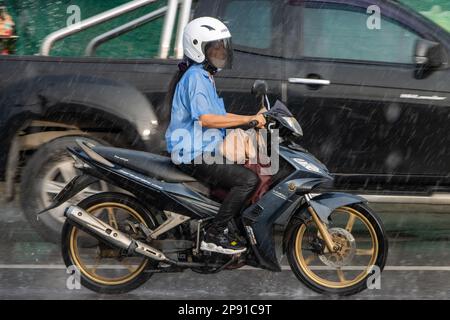 SAMUT PRAKAN, THAILAND, 21 2022. September, Eine Frau fährt bei starkem Regen Motorrad auf der Straße Stockfoto