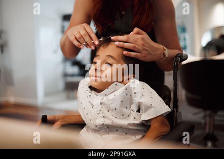 Friseur, Behinderung und Rollstuhl behindertes Kind mit zerebraler Lähmung bekommt Frisur im Salon. Junge spezielle Bedürfnisse Kind in Mexiko immer Stockfoto