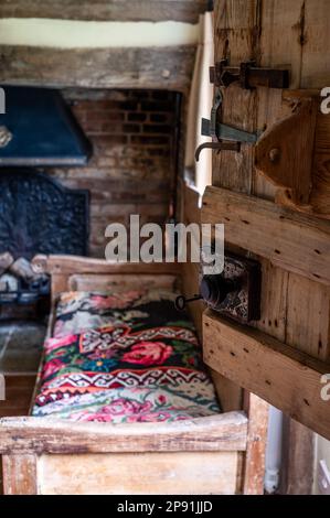 Eichenbank aus dem 17. Jahrhundert mit weißem Teppich im Tudor-Bauernhaus aus dem 16. Jahrhundert, Suffolk, Großbritannien. Stockfoto