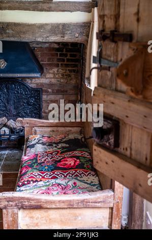 Eichenbank aus dem 17. Jahrhundert mit weißem Teppich im Tudor-Bauernhaus aus dem 16. Jahrhundert, Suffolk, Großbritannien. Stockfoto