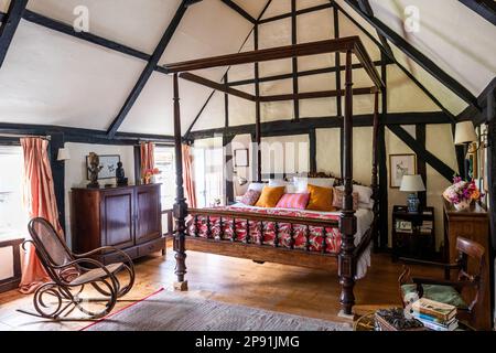 Anglo-indisches Himmelbett mit mexikanischem Durchgangsbett in doppeltem Dachgeschoss-Schlafzimmer des Tudor-Bauernhauses aus dem 16. Jahrhundert, Suffolk, Großbritannien. Stockfoto