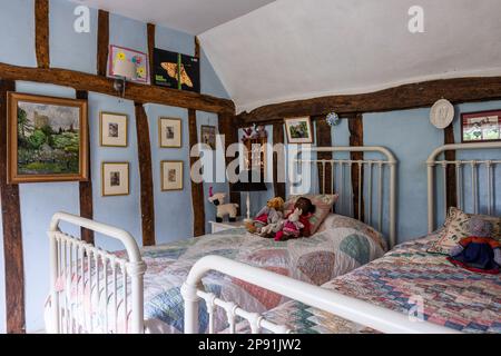 Stoffspielzeug auf Patchwork-Decke im Zweibettzimmer des Bauernhauses 16. Century Tudor, Suffolk, Großbritannien. Stockfoto