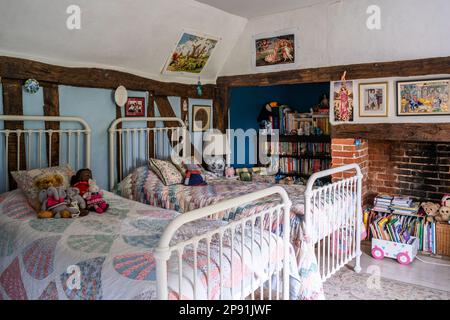 Stoffspielzeug und Bücher mit Patchwork-Steppdecken im Zweibettzimmer des Bauernhauses 16. Century Tudor, Suffolk, Großbritannien. Stockfoto