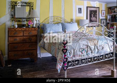 Gestickte Herzen und Patchwork-Decke in einem holzgerahmten Schlafzimmer des Bauernhauses Tudor aus dem 16. Jahrhundert, Suffolk, Großbritannien. Stockfoto