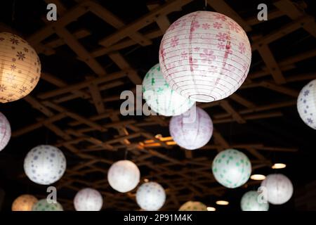 Viele weiße Runde chinesische Papierlaternen hängen in der Dunkelheit. Hypochondrischen Lampen Beleuchtung in der Nacht Stockfoto