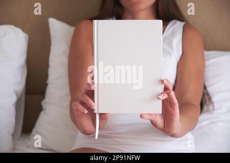 Junge Frau mit leerem Notizbuch oder Buchmodell, die das Cover-Design präsentiert. Stockfoto