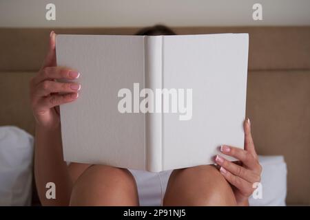 Junge Frau mit leerem Notizbuch oder Buchmodell, die das Cover-Design präsentiert. Stockfoto