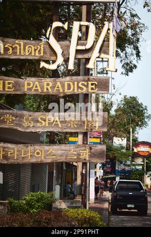 Pattaya, Thailand - 22. März 2016: Sehr altes Holzschild auf einer Straße mit der Aufschrift: The Paradise Spa in 4 verschiedenen Sprachen. Überstand billige Werbung in Stockfoto