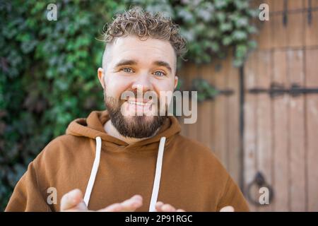 Ein hübscher, lockiger Mann nimmt ein Video von sich auf - Video-Blog und Jugend-Blogger-Konzept Stockfoto