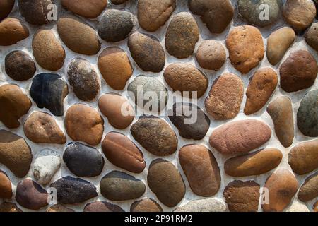 Graue und braune Kiesel Mosaikwand strukturierten Hintergrund. Gekachelte Stein Dekoration Design Hintergrund Stockfoto