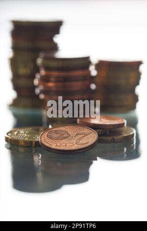 Vier Euro-Münzen vor Stapeln gespiegelter Münzen Stockfoto