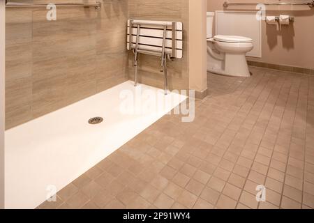 Rollstuhlgerechtes Hotelbadezimmer mit Dusche mit Fliesenboden und Wänden. Stockfoto