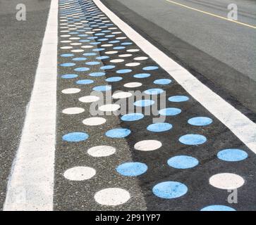 Fußgängerübergang auf Asphaltstraße mit blauen und weißen Punkten Stockfoto