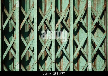 Blaugrüne Farbe alten rostigen Falten gate Hintergrund. Grüne geometrische Muster Gitter zum Store Eingang. Geschlossen asiatischen Shop detail Stockfoto